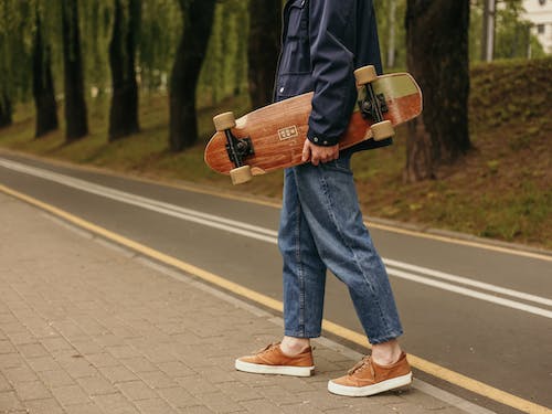 Man in Blue Denim Jeans and Black Jacket Holding A Skateboard