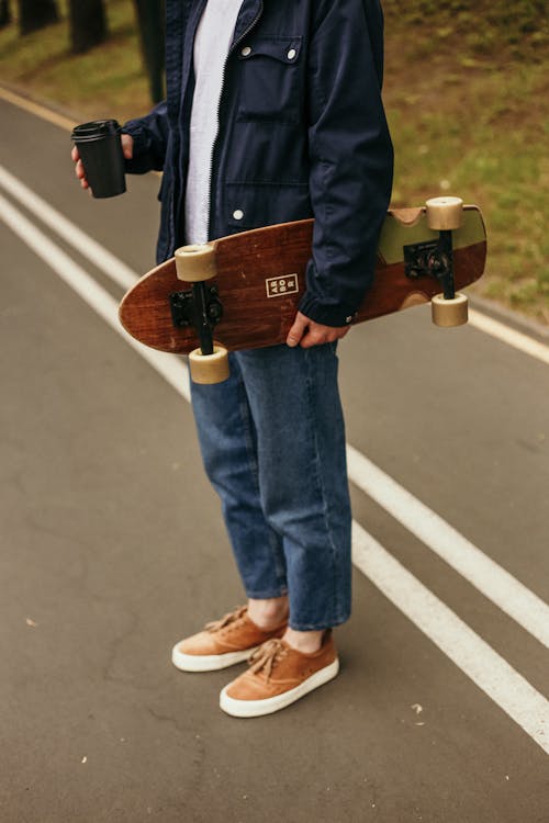 Free Person Holding Longboard and Coffee Drink Stock Photo