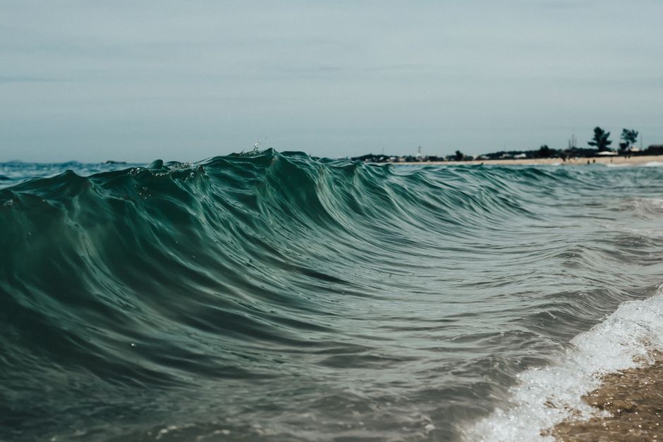 Captivating view of an ocean wave crashing gracefully on a sandy beach with a serene horizon.