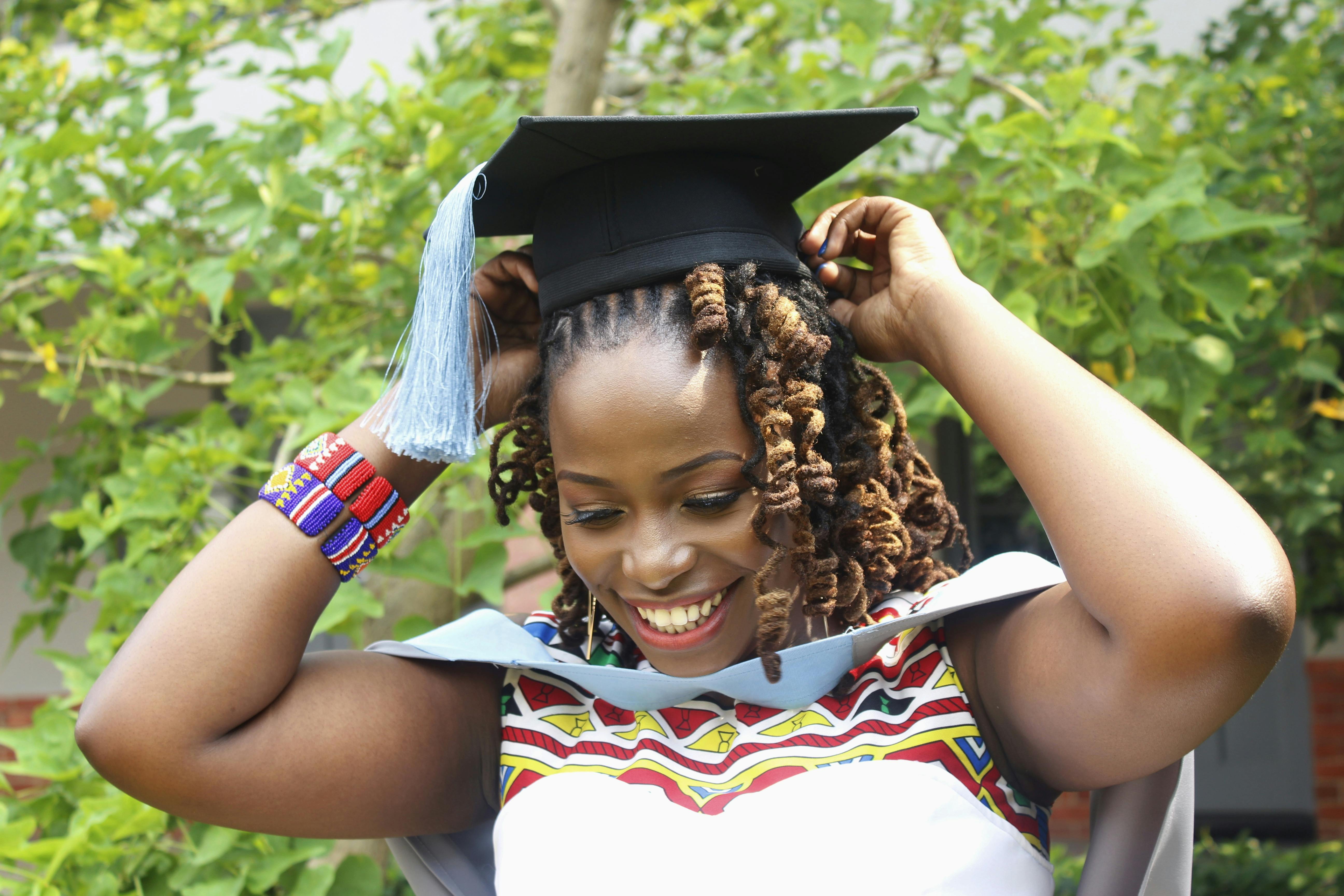 一位快乐的女子在户外举起双臂庆祝毕业