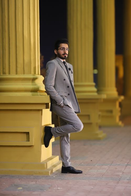 Free Elegant man in plaid suit leaning against a column at night in Multan, Pakistan. Stock Photo