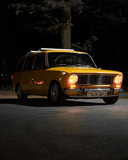 Yellow Vintage Car Parked on Road during Night Time