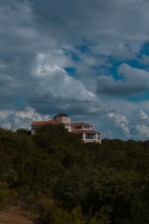 Dense clouds over house on slope among trees