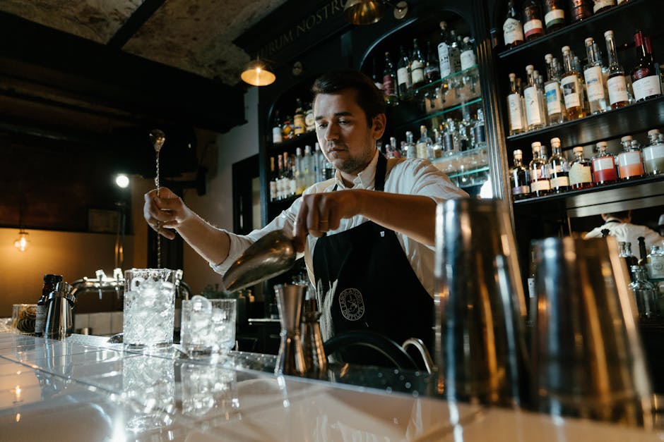 Bartender expertly mixing a cocktail with a shaker and jigger - female bartender uniform Bartender expertly mixing a cocktail with a shaker and jigger - female bartender uniform