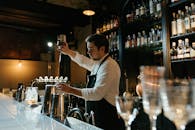 Man in White Long Sleeve Shirt Pouring Wine on Clear Wine Glass