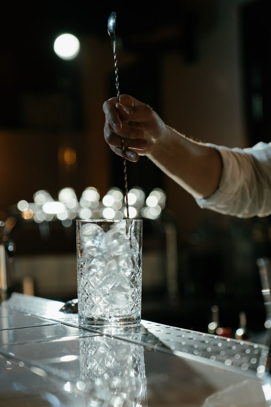 bartender stirring cocktail in dim light