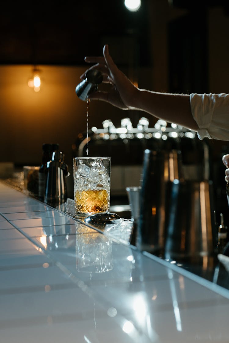 Person Pouring Water On Clear Drinking Glass