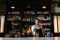 Man in White Dress Shirt Sitting on Chair in Front of Bar Counter