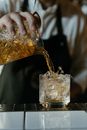 Person Pouring Brown Liquid on Clear Drinking Glass
