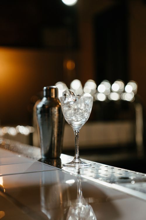 Free A stylish scene with a cocktail shaker and glass on a bar counter, featuring bokeh lights. Stock Photo