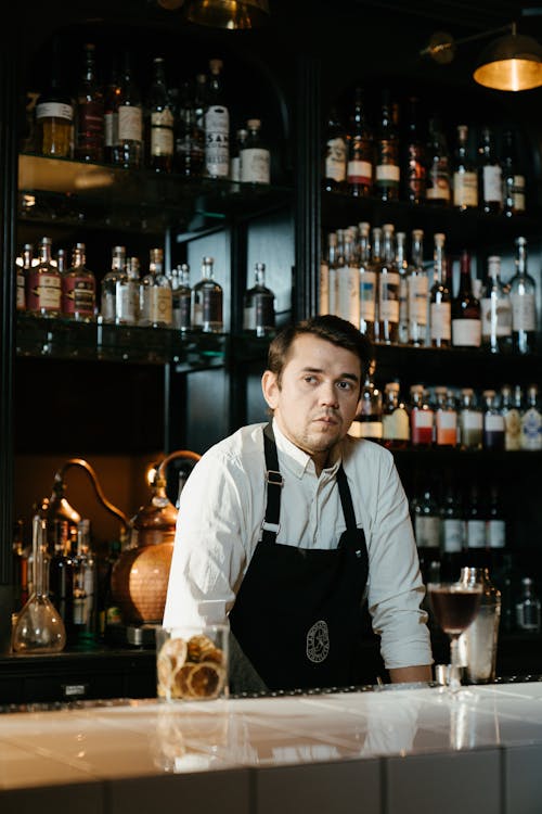 Man in White Dress Shirt Standing Near Wine Bottles