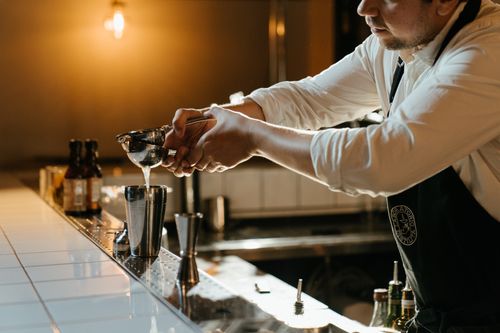 Free Bartender squeezing fresh lime juice into a shaker for a cocktail at a stylish bar. Stock Photo