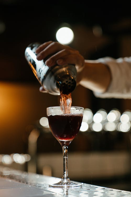 Person Pouring Red Wine on Clear Drinking Glass