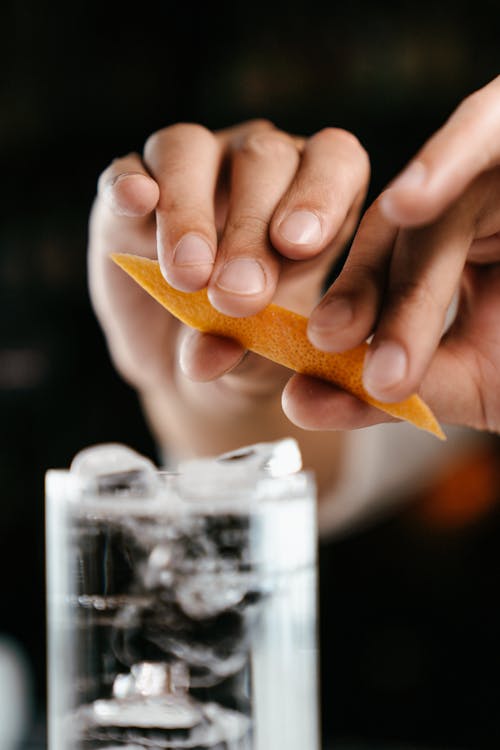 Person Holding Clear Drinking Glass With Brown Liquid