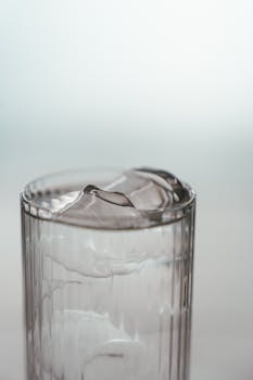 Close-up of a highball glass with ice and water ripples, offering refreshing details.