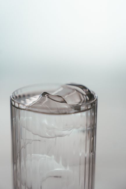 A tall highball glass filled with ice, whiskey, and club soda, with a lemon twist resting on the rim and small bubbles rising through the drink.