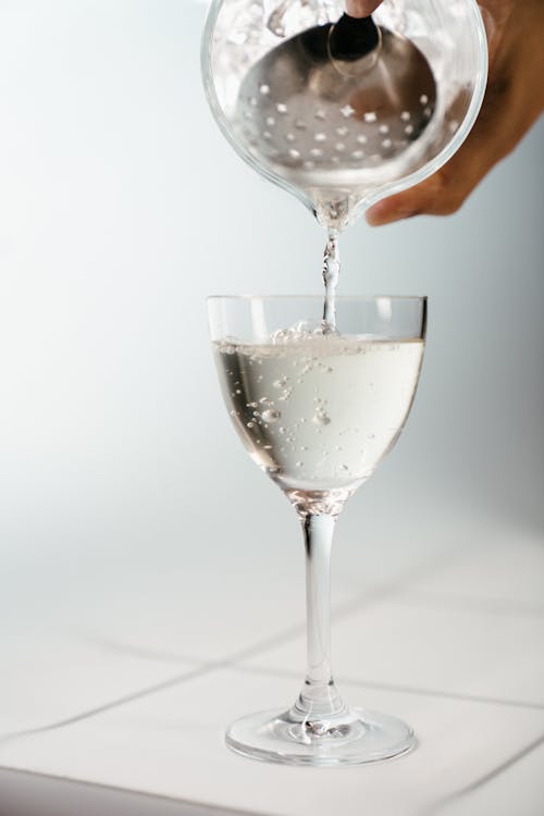 Person, Die Wasser Auf Klares Weinglas Gießt
