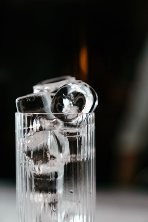 Free Close-up of clear ice cubes stacked in a glass with a dark background, symbolizing refreshment. Stock Photo