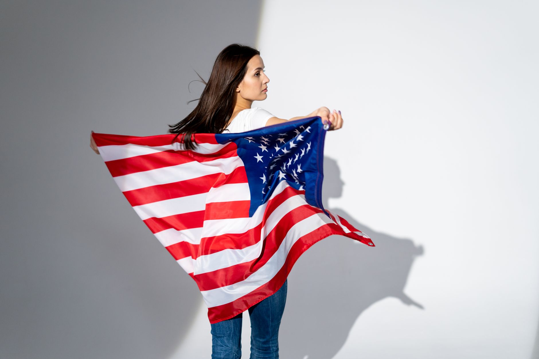 Woman standing with an American flag, symbolizing patriotism and national pride.