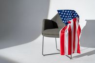 A stylish armchair with an American flag draped over it, symbolizing patriotism.
