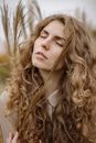 卷发女子的亲密特写被户外麦秆簇拥着