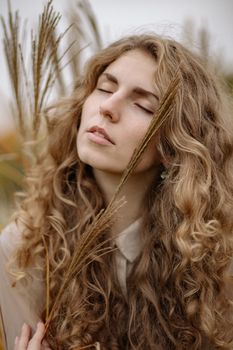 卷发女子的亲密特写被户外麦秆簇拥着
