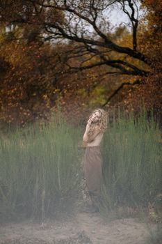 秋天，薄雾缭绕的森林里，一名卷发女子正在摆姿势