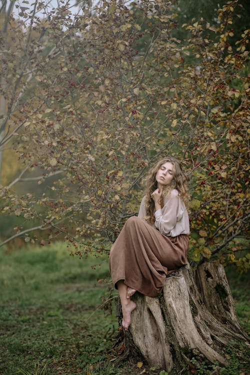 A Woman Sitting on a Tree Stump