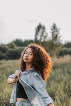 自信的女人在田野里自然地摆着姿势，展现休闲时尚风格