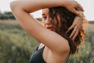 一个迷人的肖像，一个女人的卷发在日落时优雅地在户外摆姿势