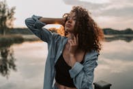 日落时分，一位美丽的女人在宁静的湖边摆出优雅的姿势，尽显时尚