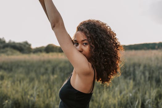 白天，一名卷发的年轻女子在田野里摆姿势