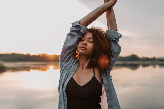 一位卷发女子在水边宁静地享受日落