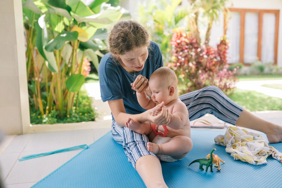 Mãe e bebê brincando em tapete de jardim ensolarado