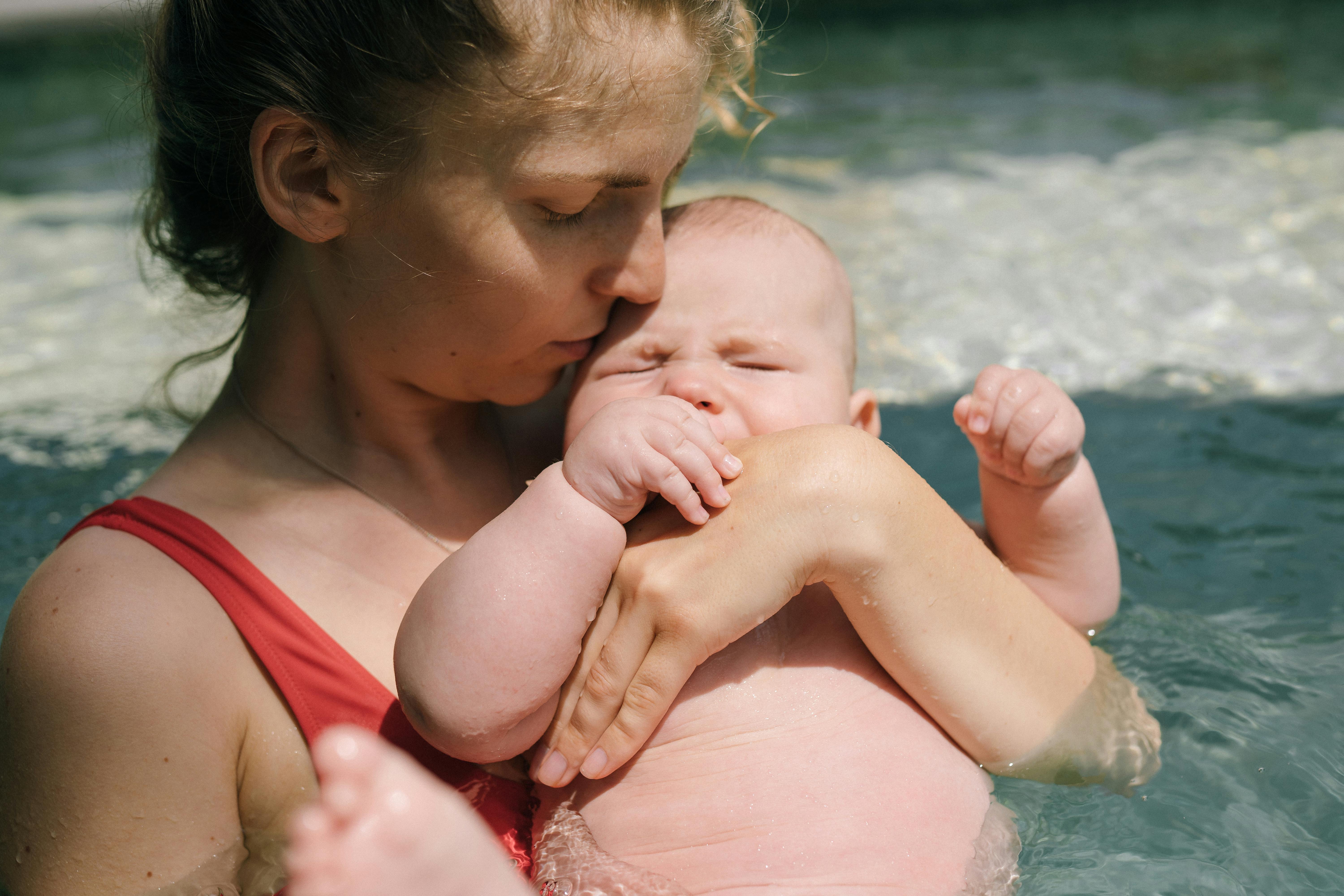 close up photo of mother carrying her baby in the swimming pool