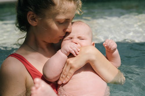 Free Close-Up Photo of Mother Carrying Her Baby in the Swimming Pool Stock Photo