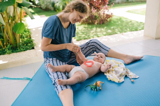 阳光明媚的日子里，微笑的母亲和婴儿在室外的垫子上玩耍，享受着玩具带来的乐趣