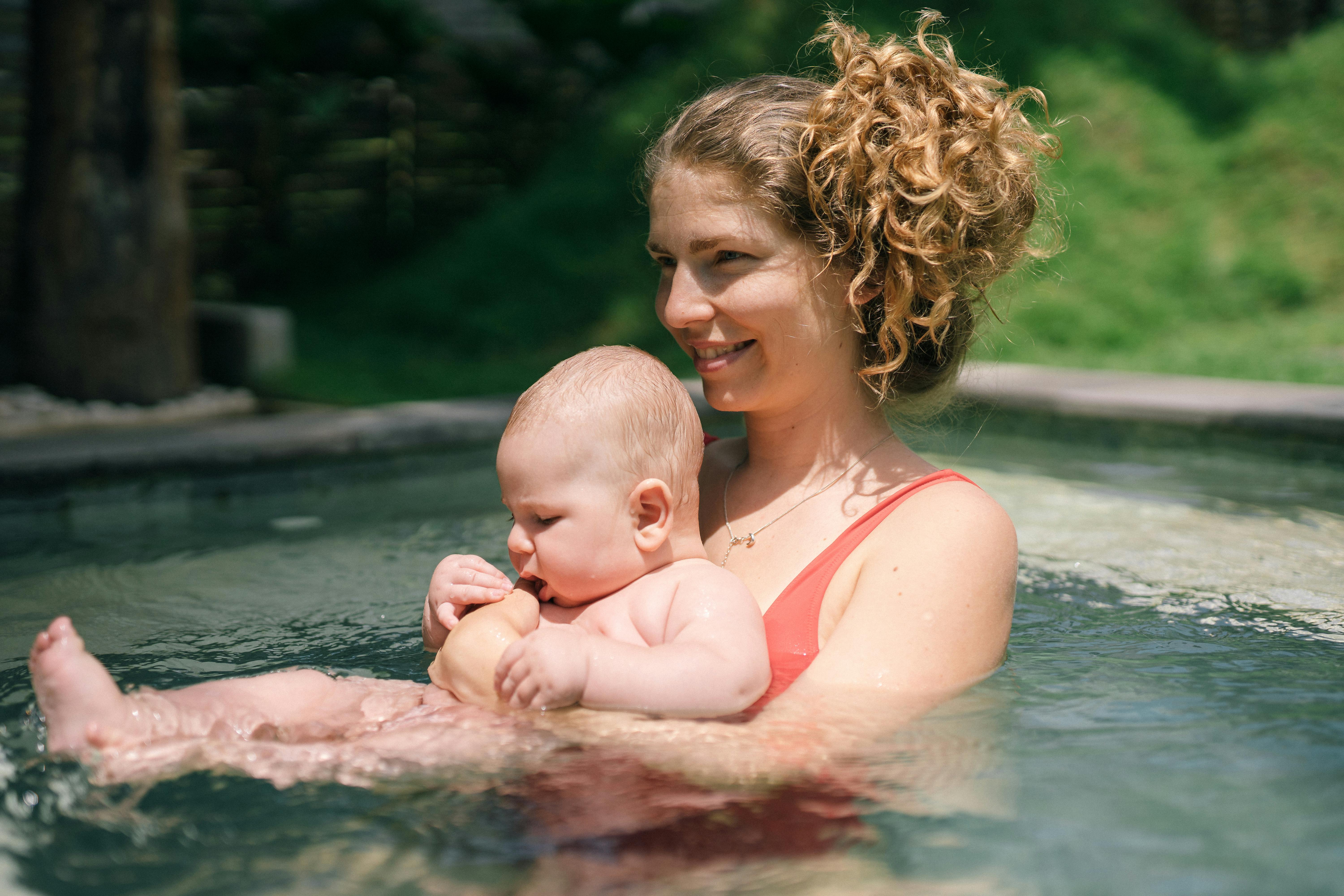 mother holding her baby in the swimming pool