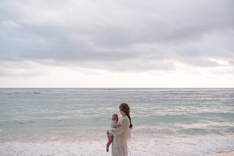 Mother Carrying Her Baby At The Beach