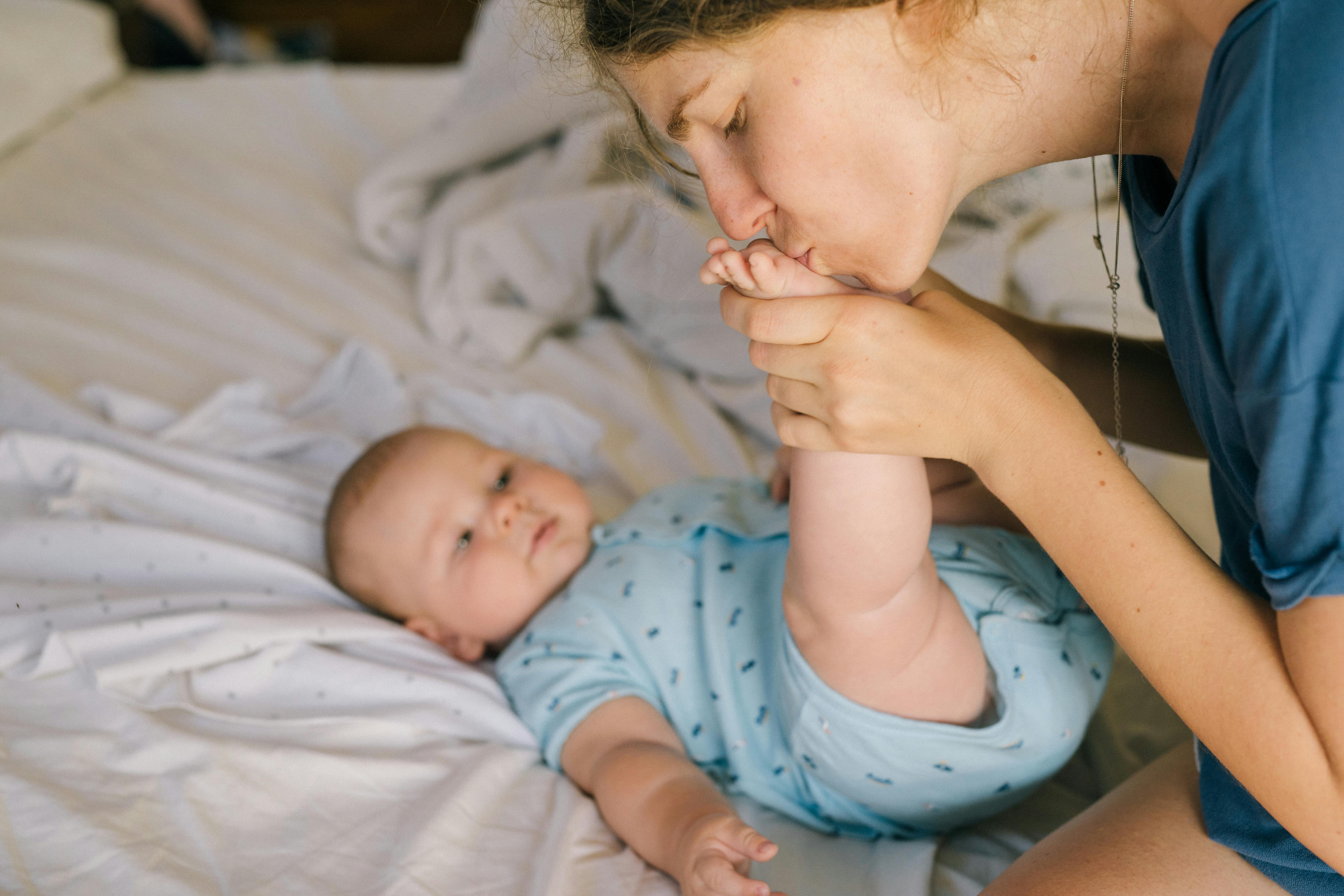 photo of woman kissing baby s foot