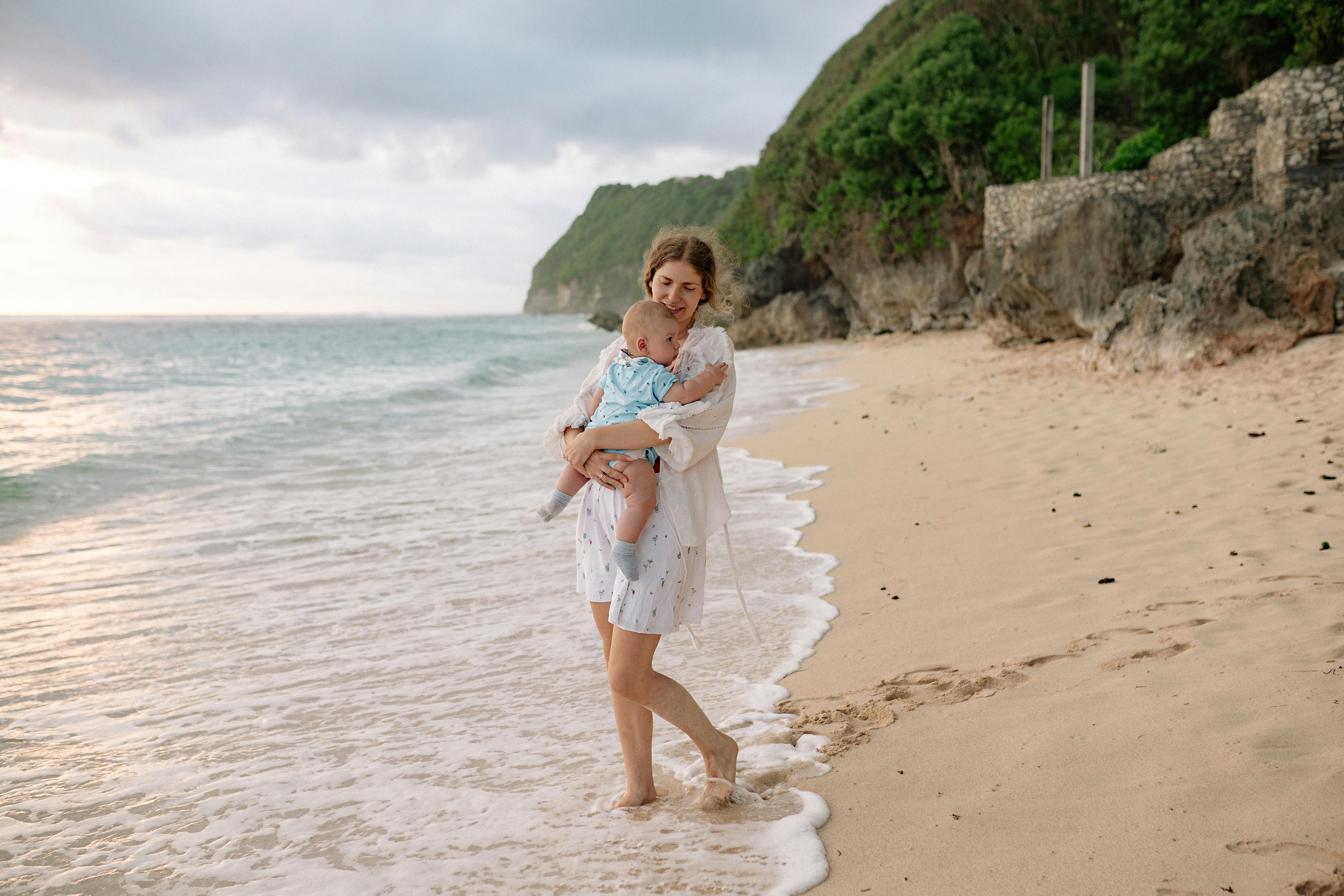 mother carrying her baby at the beach