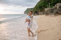 一位母亲抱着她的孩子，沿着宁静的海滩享受夏日
