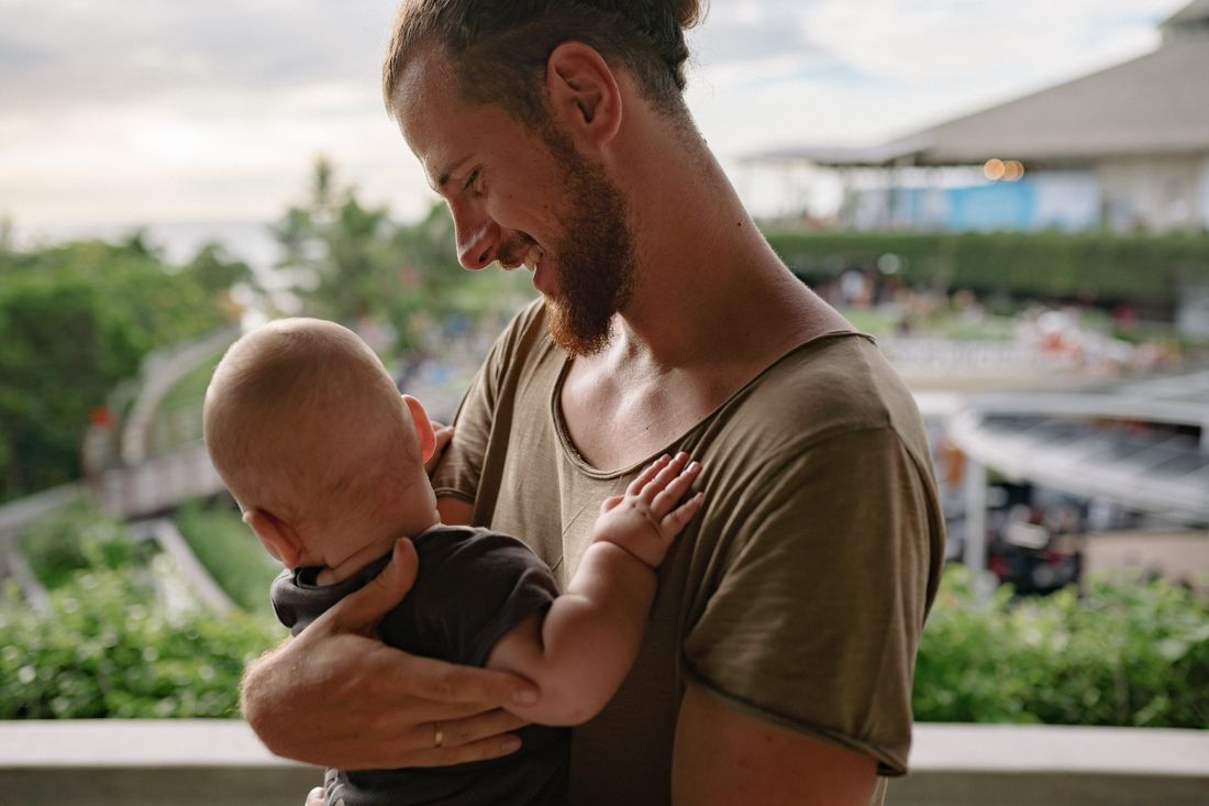 Smiling father holding his baby close on a sunny balcony