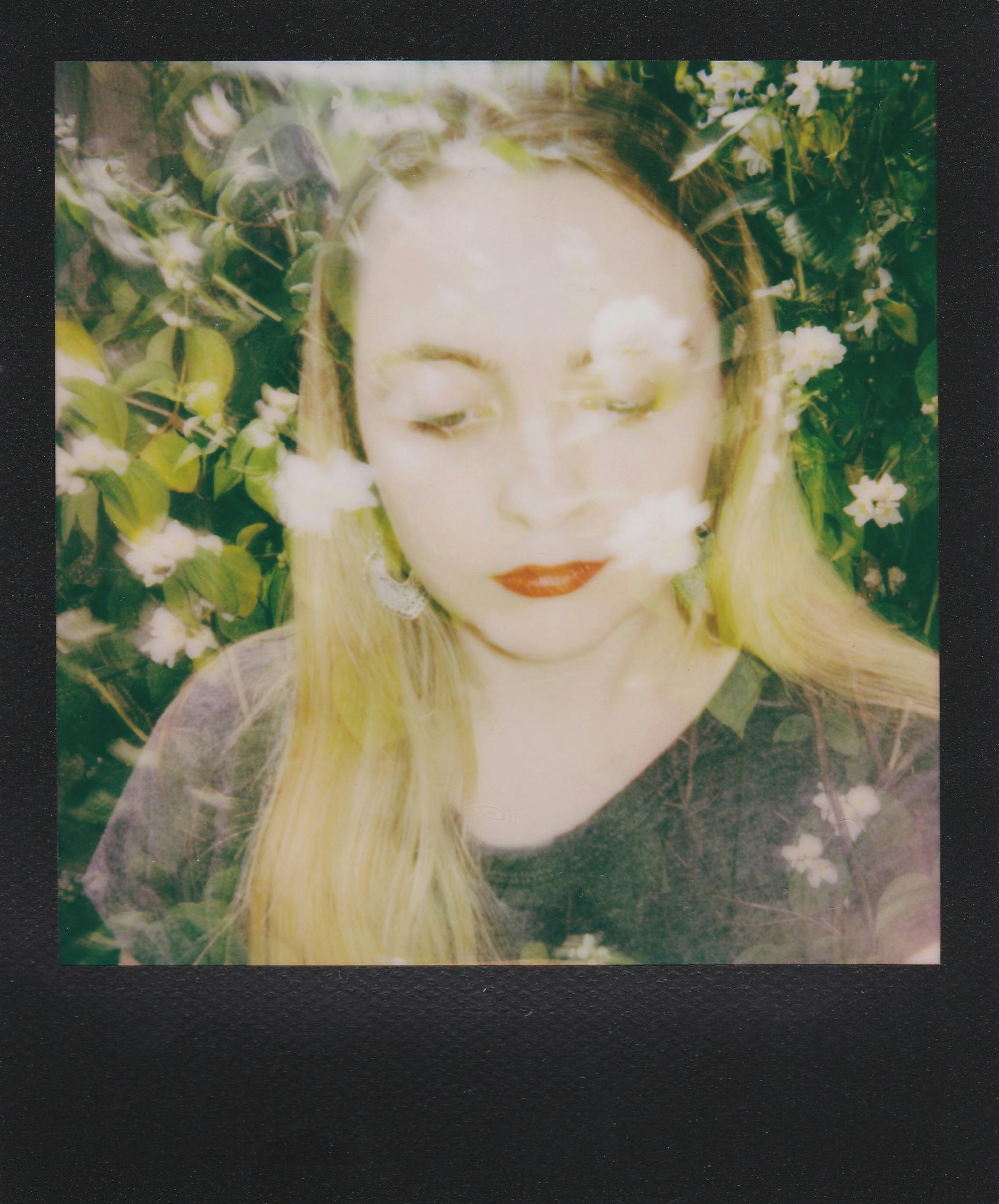 Artistic polaroid portrait of a woman surrounded by nature, eyes closed, serene expression.