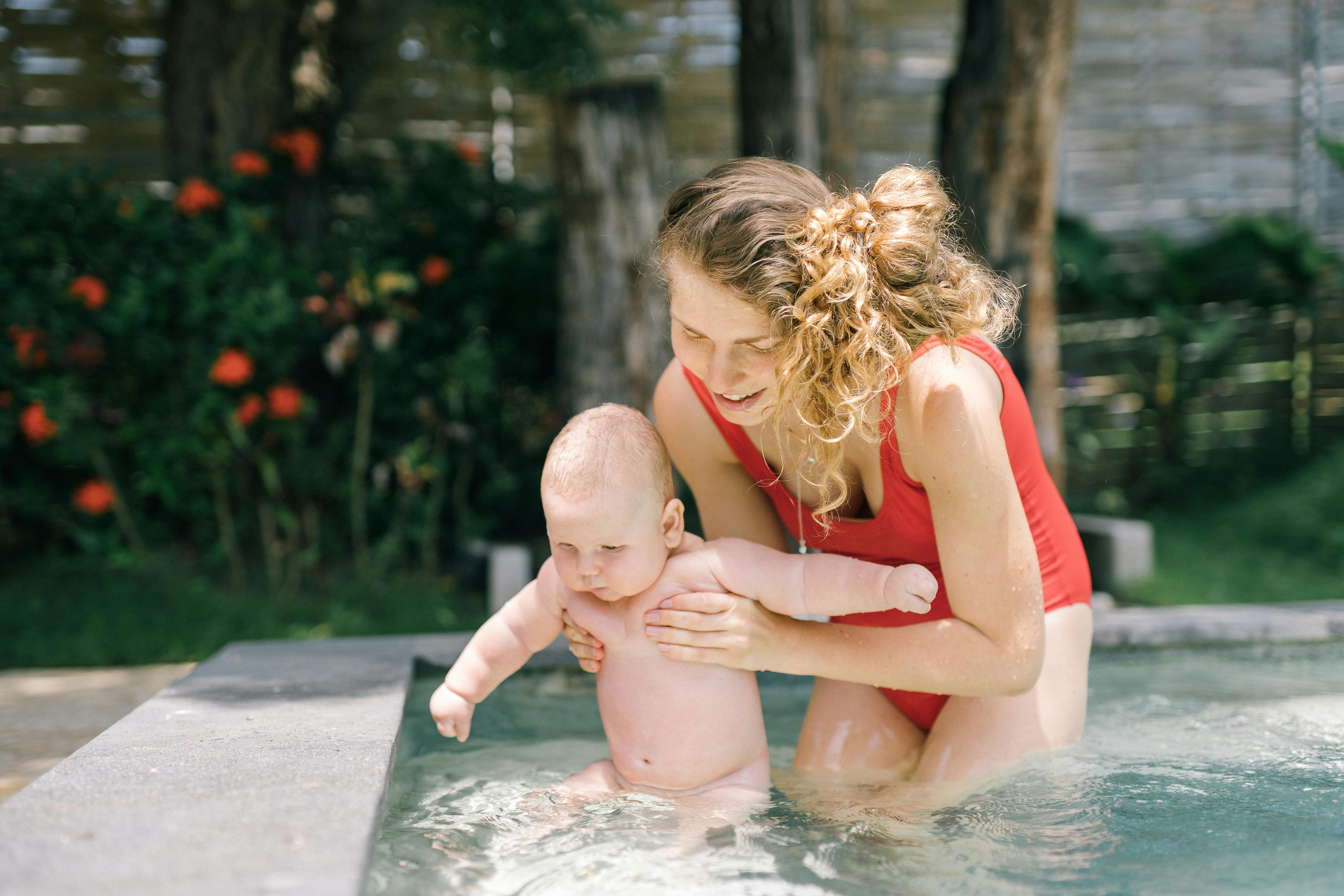 mother holding her baby in the swimming pool