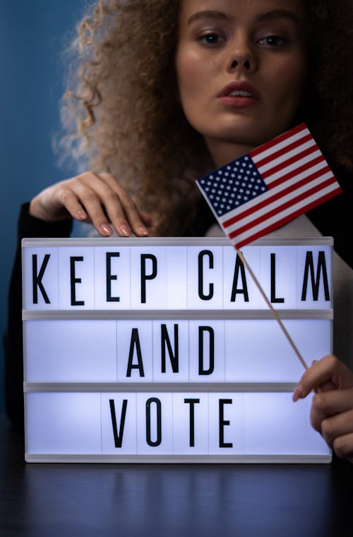 Woman Behind a Sign and Holding an American Flag