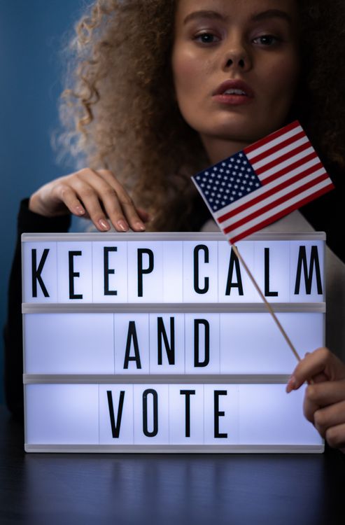 Woman Behind a Sign and Holding an American Flag · Free Stock Photo