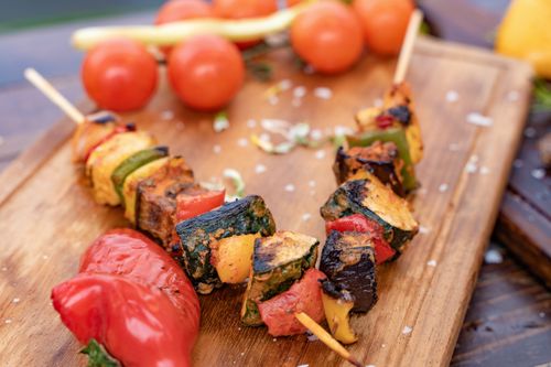Free Tasty grilled vegetable skewers on a wooden board with cherry tomatoes and spices. Stock Photo