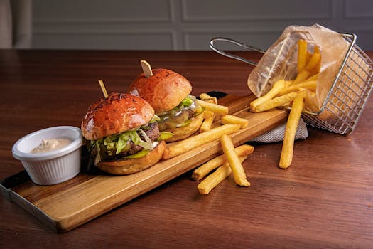 Delicious gourmet burgers with french fries on a wooden platter, perfect for a casual dining experience.