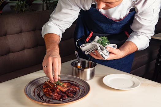 Close-up of a chef in Dubai plating a gourmet lamb dish in a restaurant.